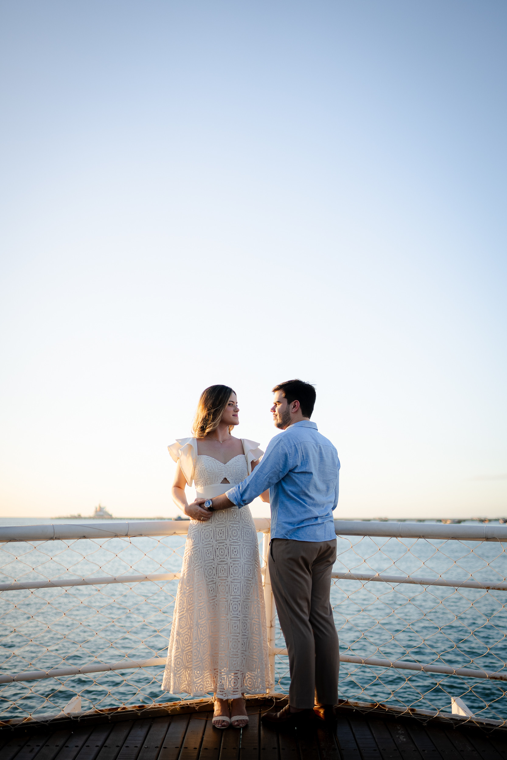 Casal junto à grade com o mar ao fundo